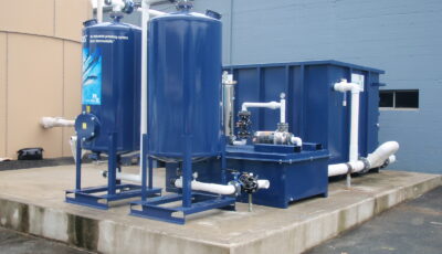 Newterra Purus polishing installation consisting of a concrete slab supprting a four pieces of equipment consisting of a shipping container, a smaller metal box, and two vertical elevated vessels
