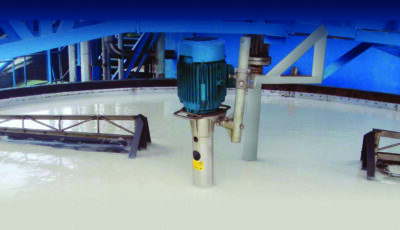 Innermost view of a Newterra microfloat dispersed air flotation DAF system where a central round tank is filled with water aerated to the point of being a milky white foam texture by an aerator mounted with metal brackets in the middle of the image with the tank structure supported by metal reinforcing structures, the view is underneath a blue support structure with stairs and various vertical metal pieces can be seen in the background