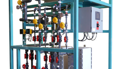 A product image with white background consisting of a cyan metal frame supporting electrodeionization technology comprised of processing units connected with various pipes with turn valves and gauges