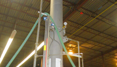 A vacuum dearator using forced air degassifiers in an industrial warehouse consisting of a large metal or concrete tube with a pressure or temperature gauge, hoses, and lever valves.