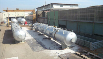 Four Cochrane counterflow deaerator units sit outside an industrial or manufacturing warehouse consisting of horizontally positioned metal vessels with numerous support points