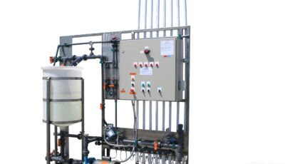 Newterra ultrafiltration system consisting of a tank, pipes, hoses, and tubing to a control panel with switches on an elevated stand.