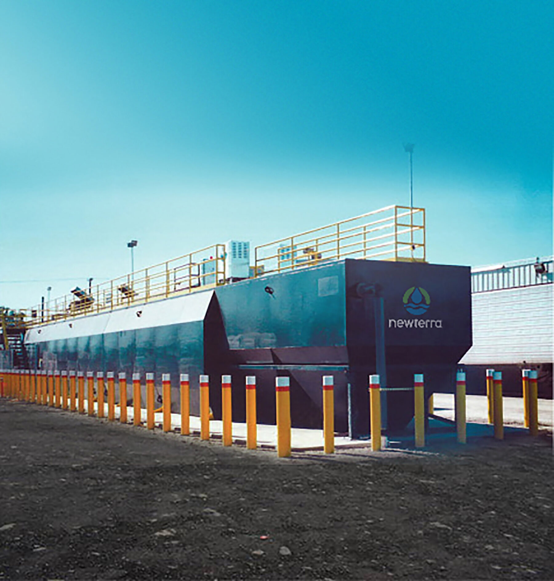 Newterra's Unisystem water treatment plant technology consisting of a large blue painted box and tank with walking railing on top and surrounded by drive proof yellow posts
