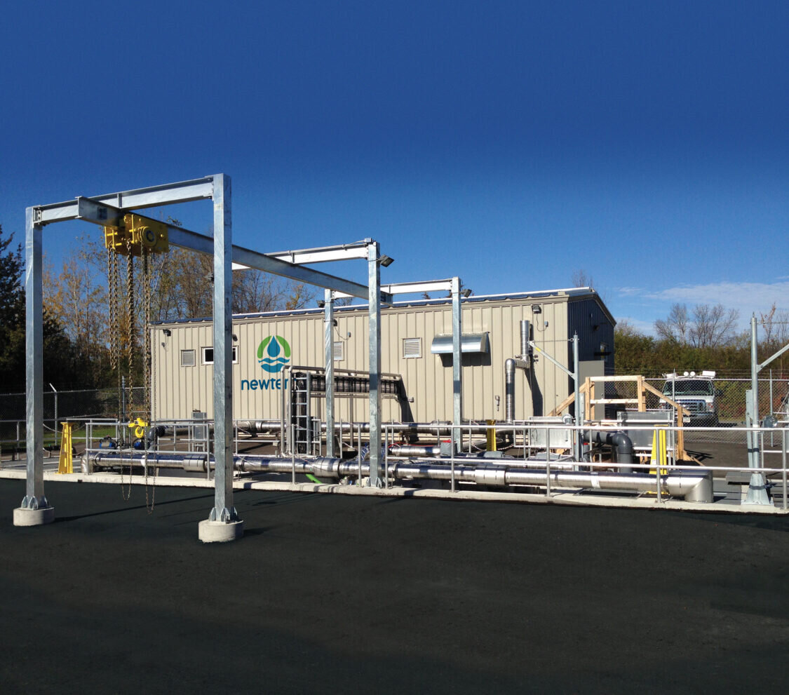 A domestic wastewater installation with a metal building and a series of pipes and a hoist attached to the exterior of the building