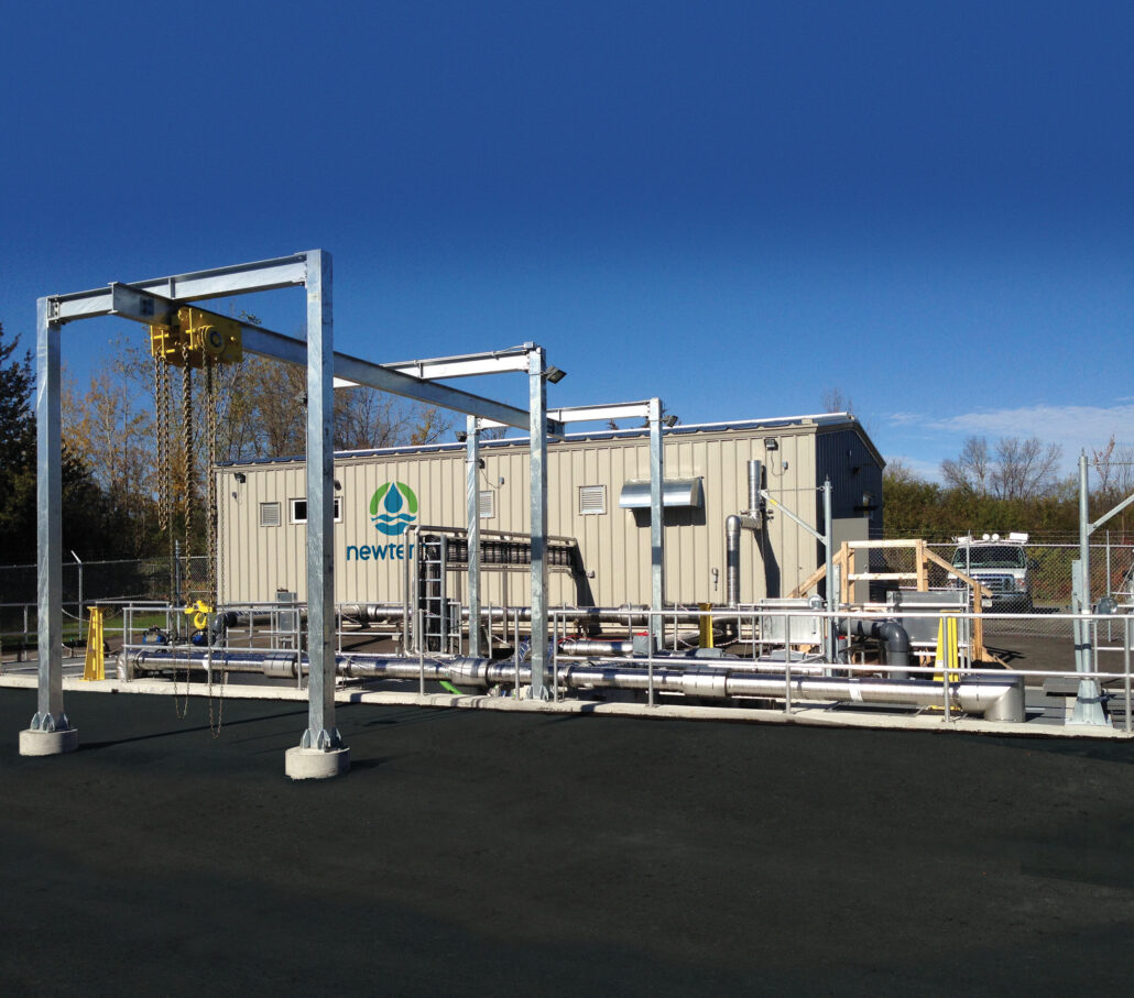 A domestic wastewater installation with a metal building and a series of pipes and a hoist attached to the exterior of the building