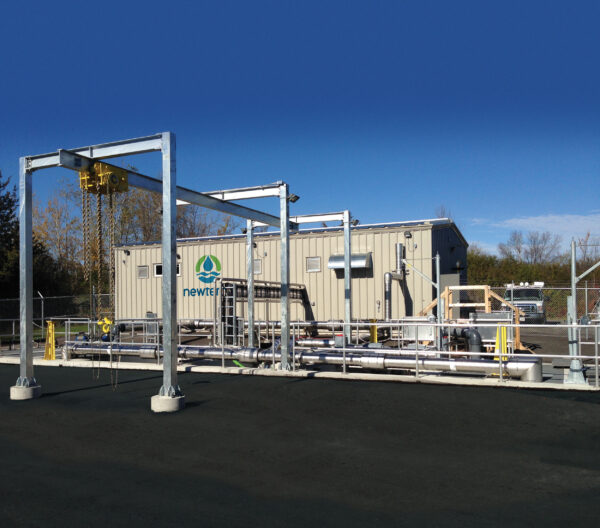 A domestic wastewater installation with a metal building and a series of pipes and a hoist attached to the exterior of the building