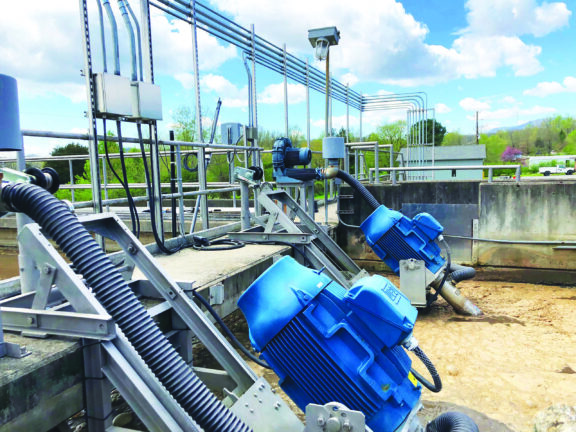 Newterra mixing aerators mix treated water with two units attached to a concrete container filled with treatment water with pipes and guard rails