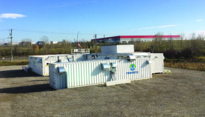 Three modular wastewater treatment technology units are oriented in a U shape near an industrial district of a medium sized metropolitan area
