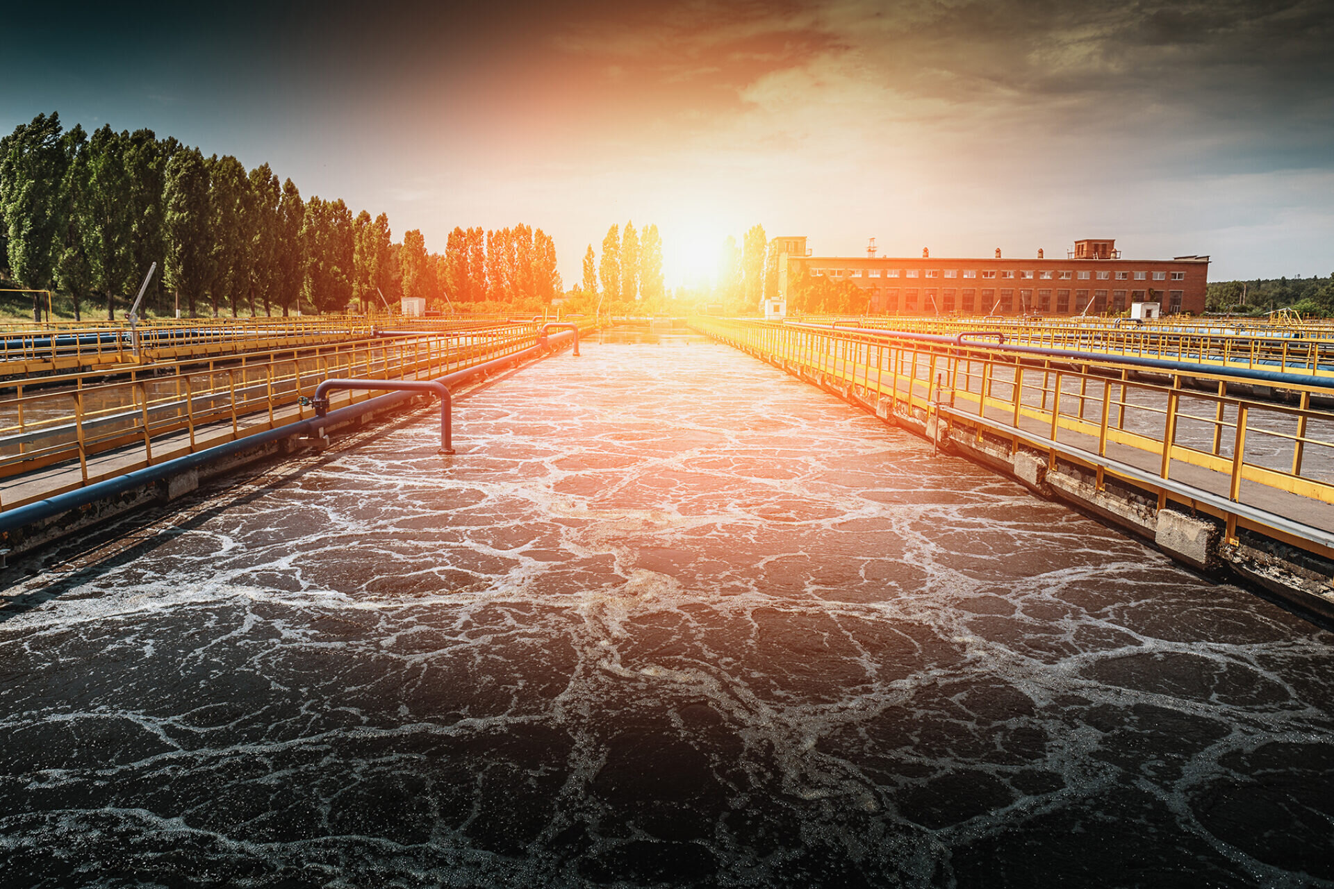 A wastewater treatment vat with guardrail supported walkwalks at sunset