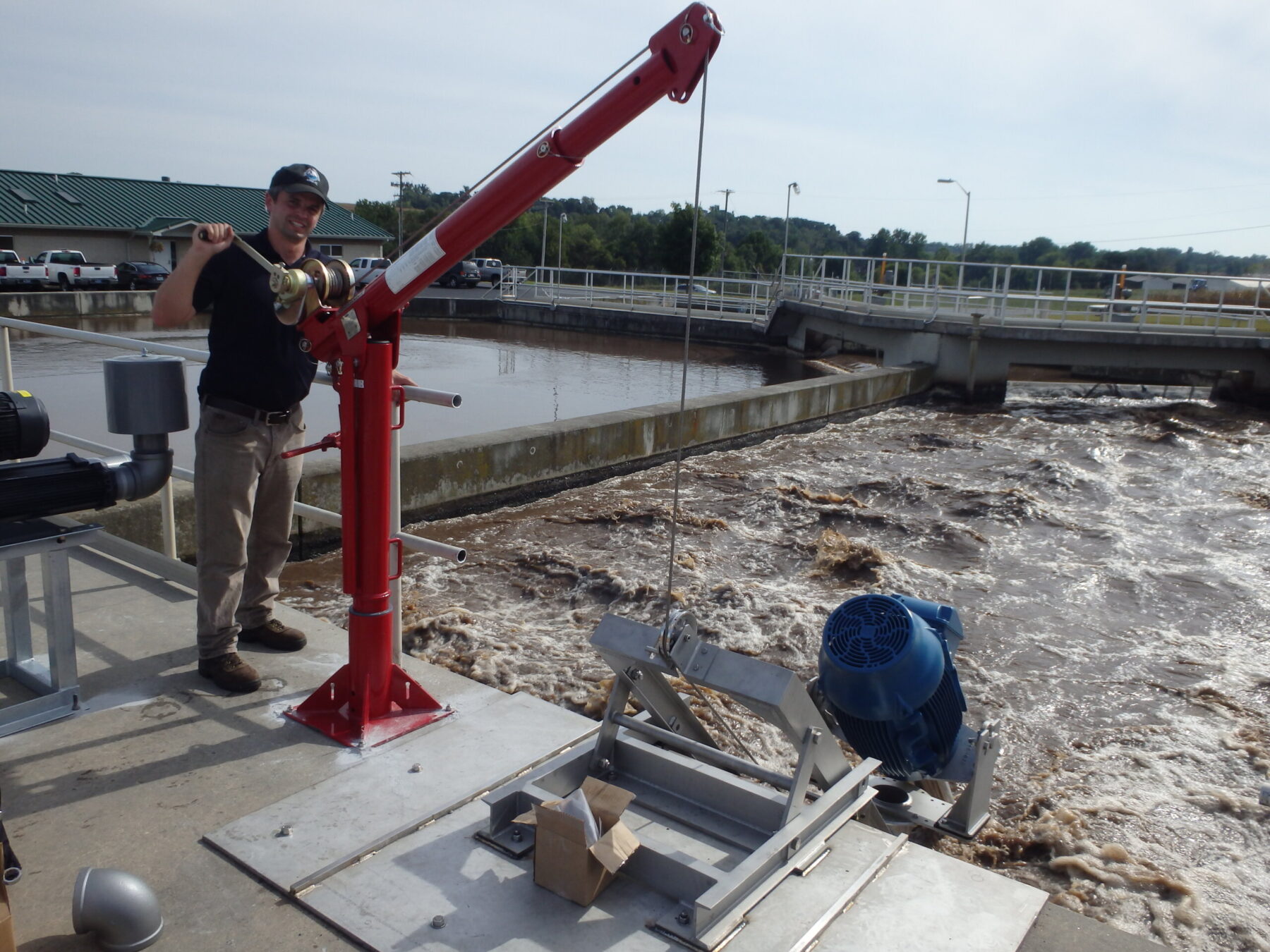 A waste water engineer operates a pulley to change the position of an aerator treating water