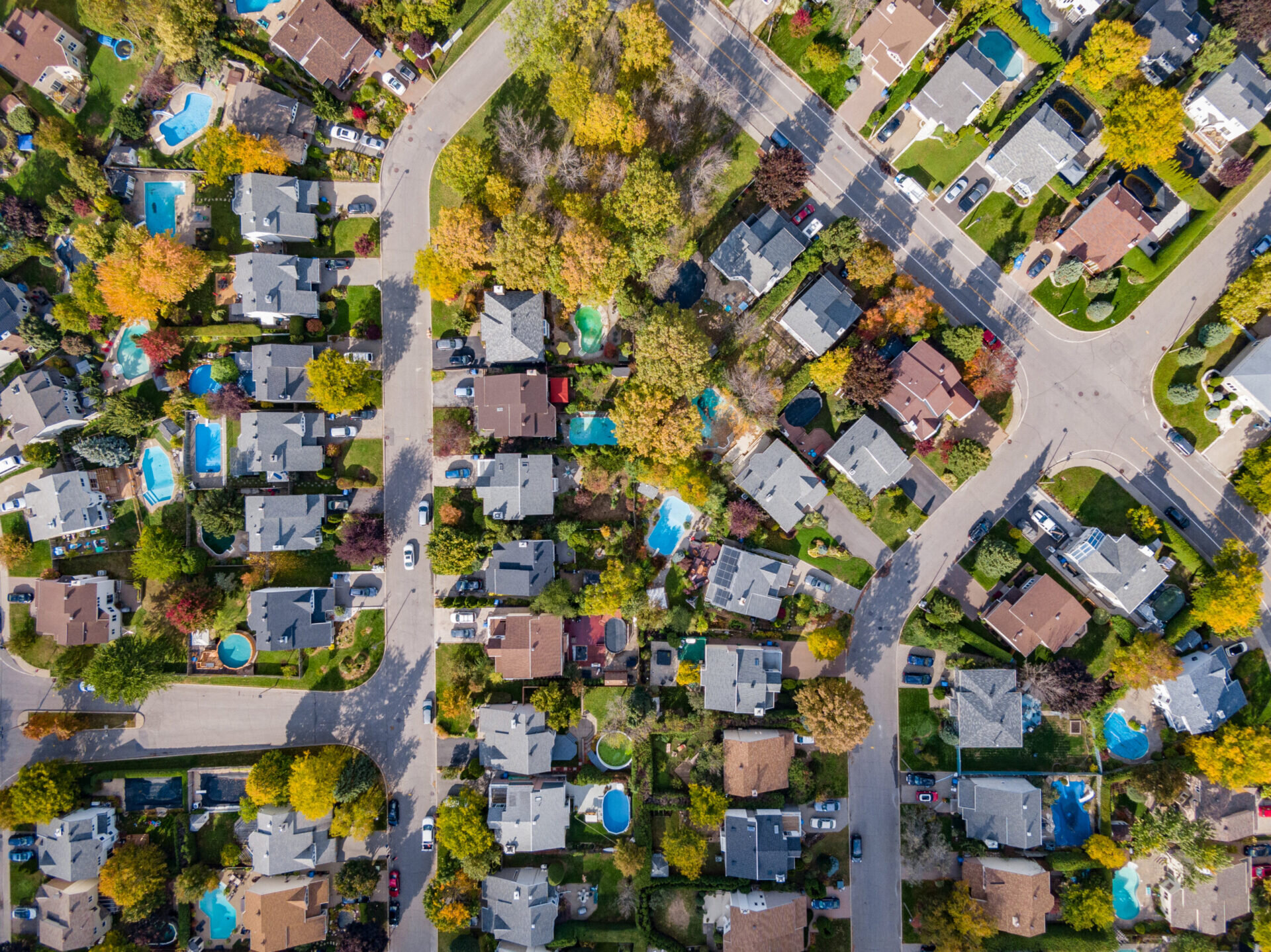 Aerial top down view of residential neighbourhood showing trees changing color during fall season in Montreal, Quebec, Canada.