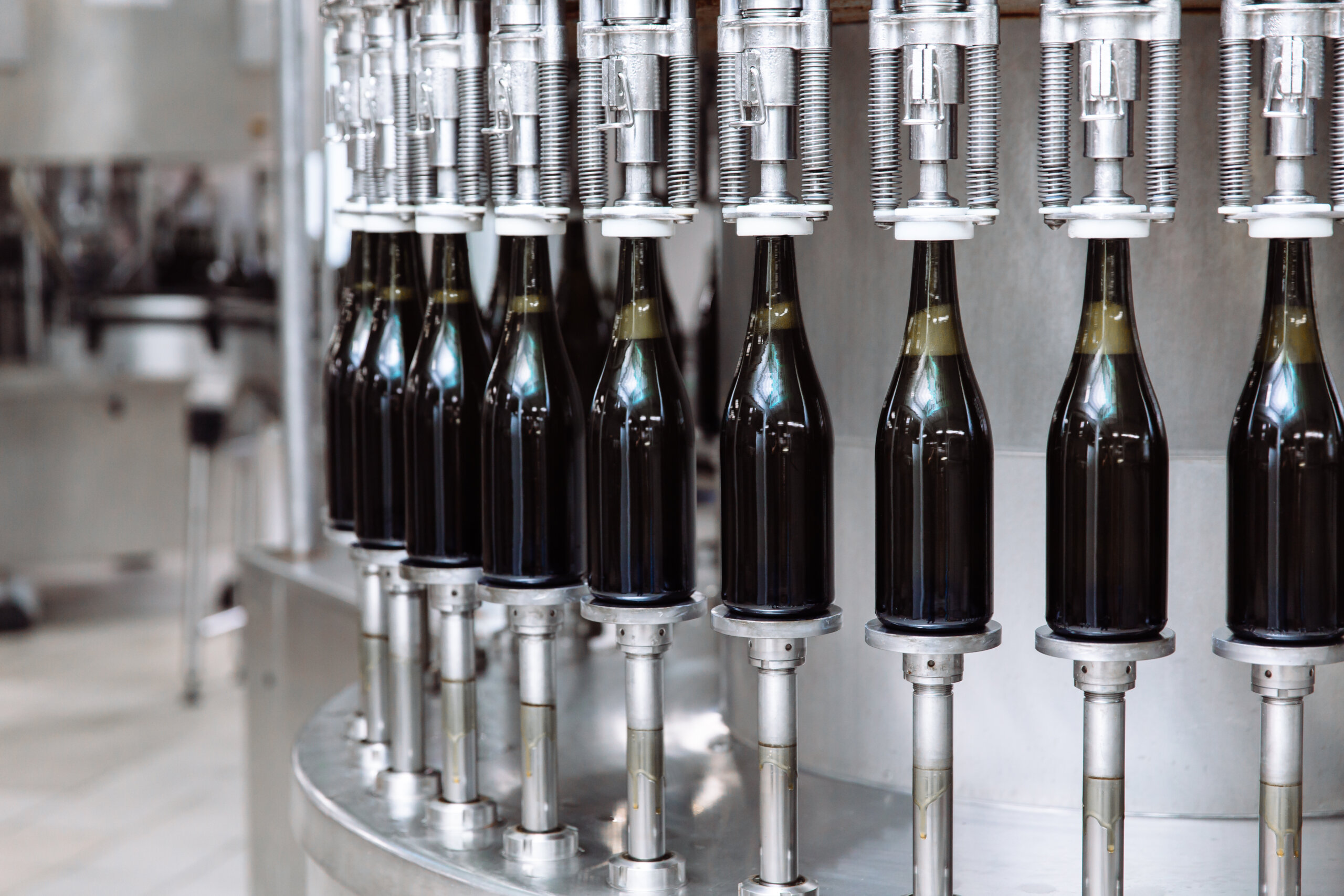 A glass bottling filling line with dark brown glass bottles being filled prior to capping