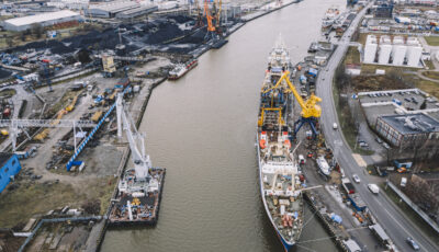 A big blue ship and yellow cranes on the water in the port of an industrial city. Cargo transportation by sea. concept. top view, aerial view