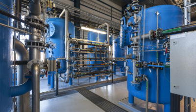 Industrial massive water filtering machinery including multiple elevated blue tanks connected by steel pipes