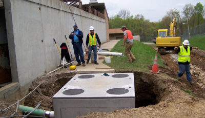 Three technicians and a manager install a Clara Gravity Separator from Newterra at a new construction site for industrial use