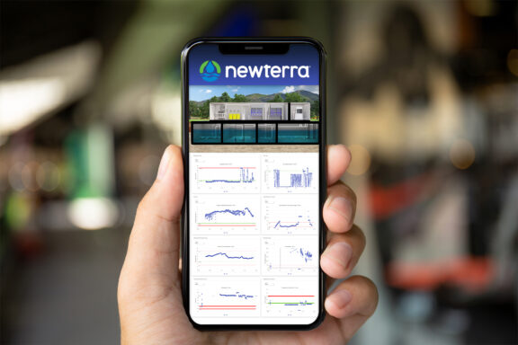 Newterra's Scada application is shown on a mobile device held by  person's left hand