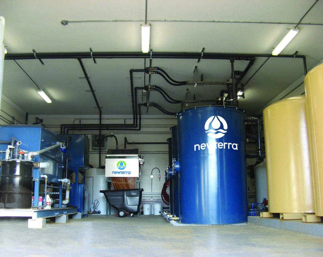Newterra technology removing iron with blue upright tanks stand in a metal sided building.