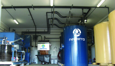 Newterra technology removing iron with blue upright tanks stand in a metal sided building.