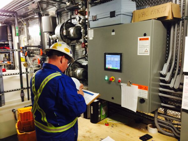 Newterra technician uses a clipboard to write notes while in industrial water treatment plant