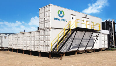 Five modular containers arranged four on lowest level and one stacked on the container closest to the photographer with black steel staircase with yellow guard rail leading to three doors in the top level container outdoors.