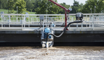 Newterra Triton aeration technology in use in a containment pond with hose and equipment on water surface and anchored to walkway platform