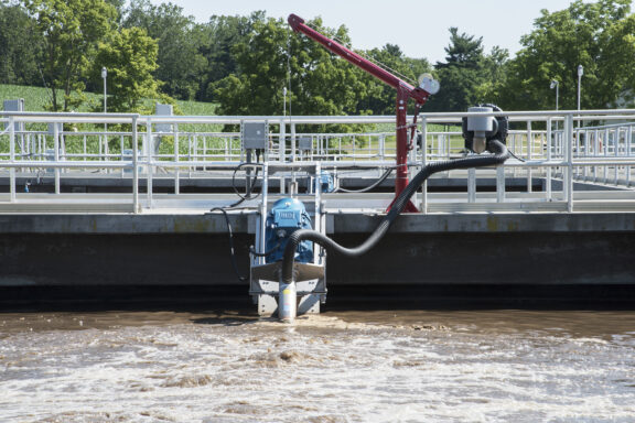 Newterra Triton aeration technology in use in a containment pond with hose and equipment on water surface and anchored to walkway platform