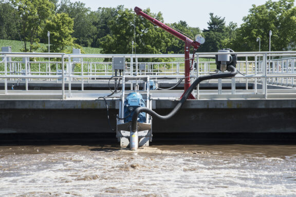 Newterra Triton aeration technology in use in a containment pond with hose and equipment on water surface and anchored to walkway platform
