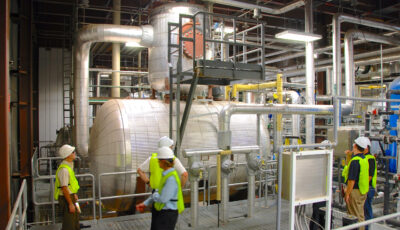 Water treatment professionals gather around a water treatment tank
