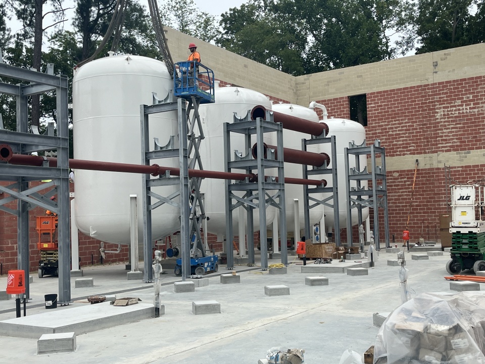 A technician on an extended lander inspecting a recently installed pressure vessel